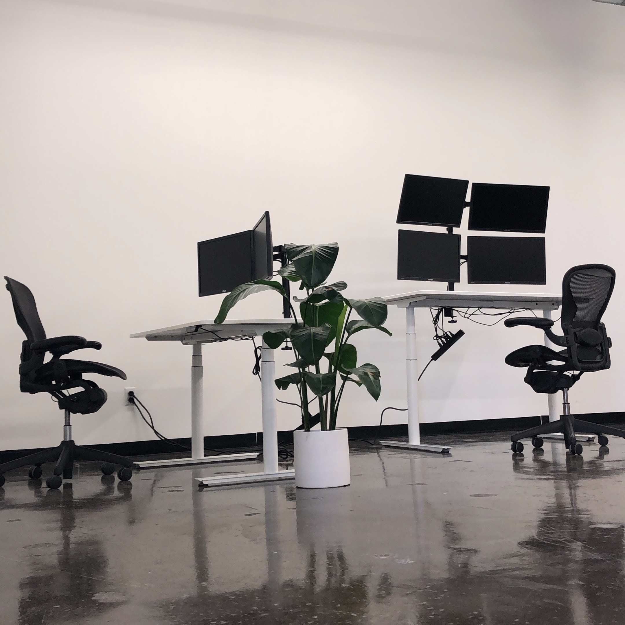 Empty modern office workspace with multiple computer monitors and ergonomic chairs