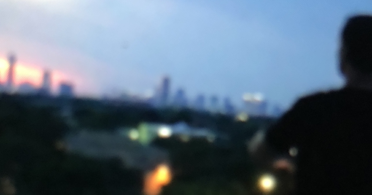 Blurry view of Houston's downtown skyline at dusk, glowing with sunset hues and vibrant city lights—symbolizing potential and urban innovation.